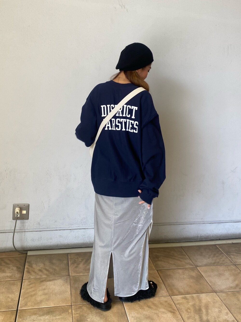 ブルー系のスウェット、グレー系のスカート、ホワイト系のショルダーバッグを着用したレディースの秋コーディネートの2枚目の写真