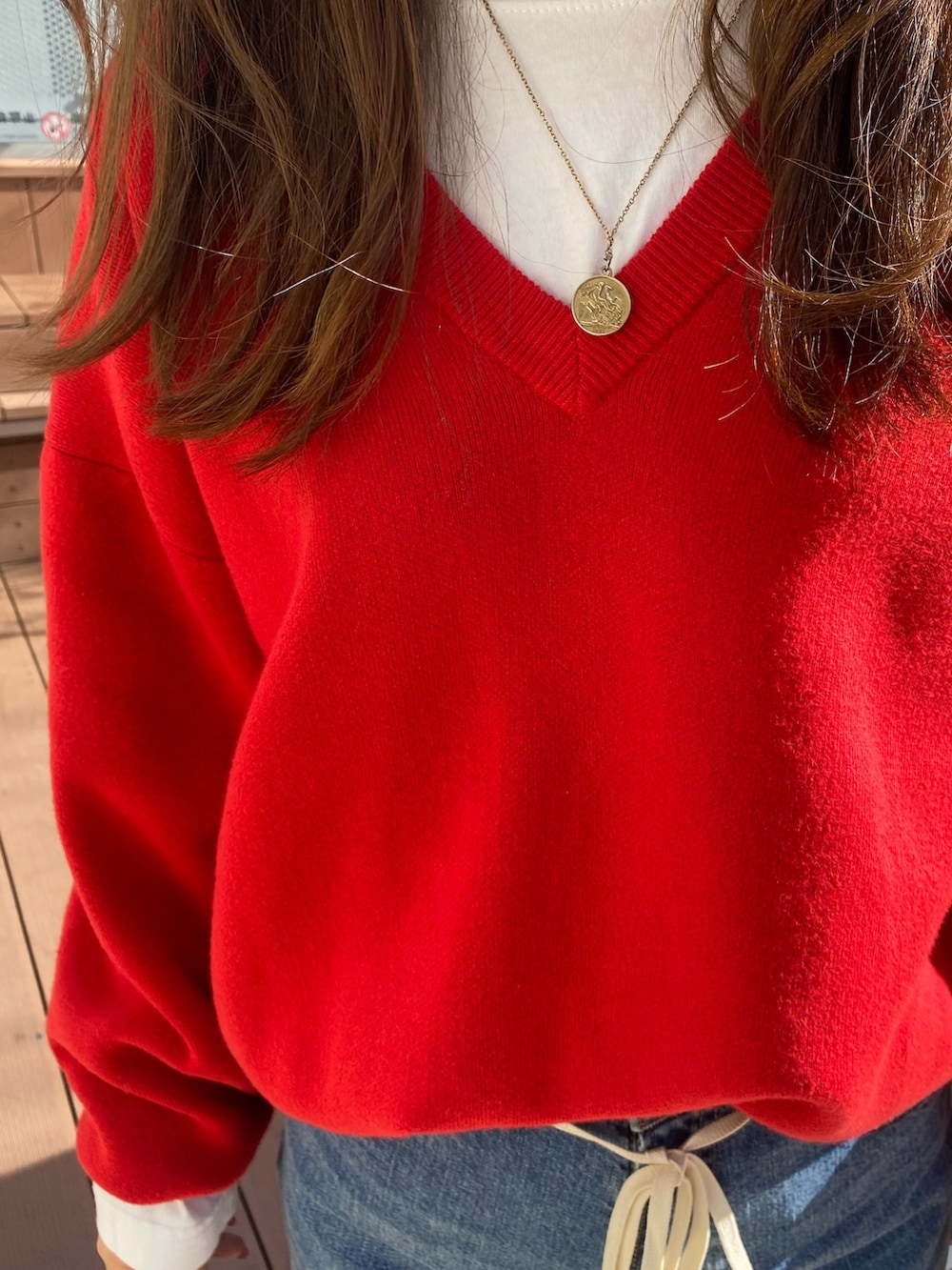 その他のチェスターコート、ブルー系のデニムパンツ、レッド系のニット/セーターを着用したレディースの冬コーディネートの6枚目の写真