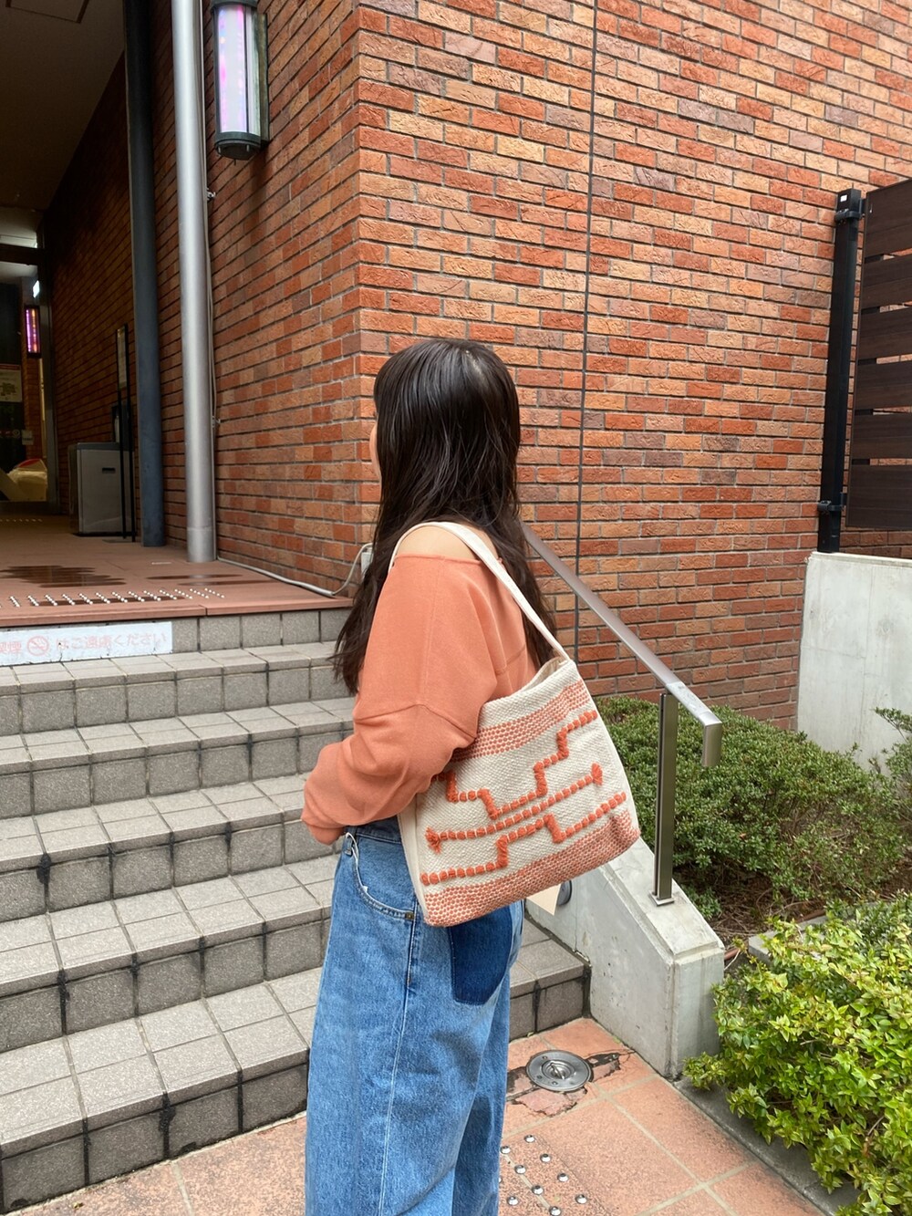 オレンジ系のニット/セーター、ブルー系のデニムパンツ、ブラック系のサンダルを着用したレディースの春コーディネートの6枚目の写真