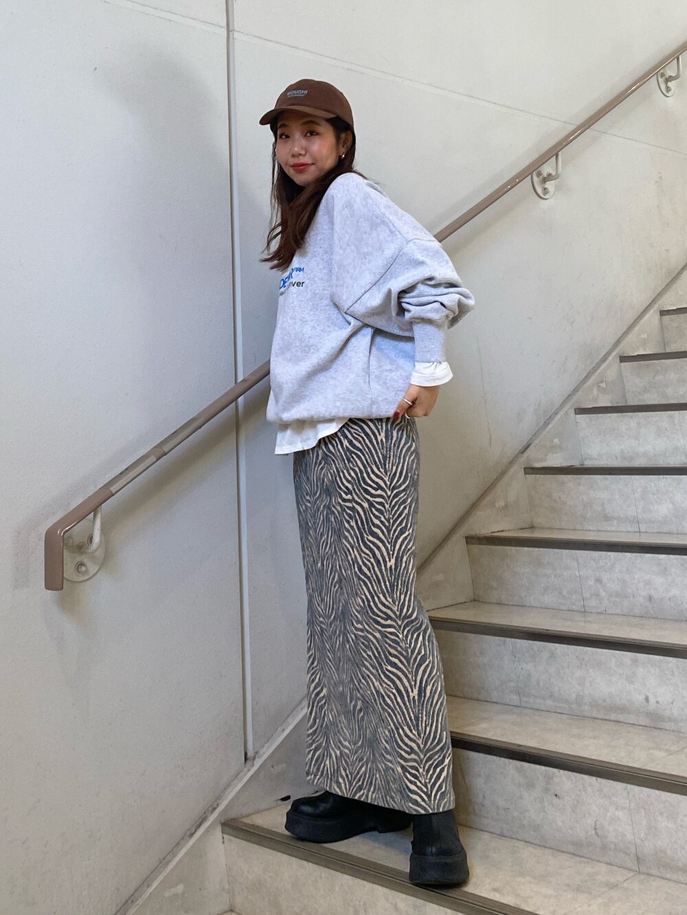 グレー系のスウェット、ブルー系のスカート、ホワイト系のTシャツ/カットソーを着用したレディースの冬コーディネートの2枚目の写真