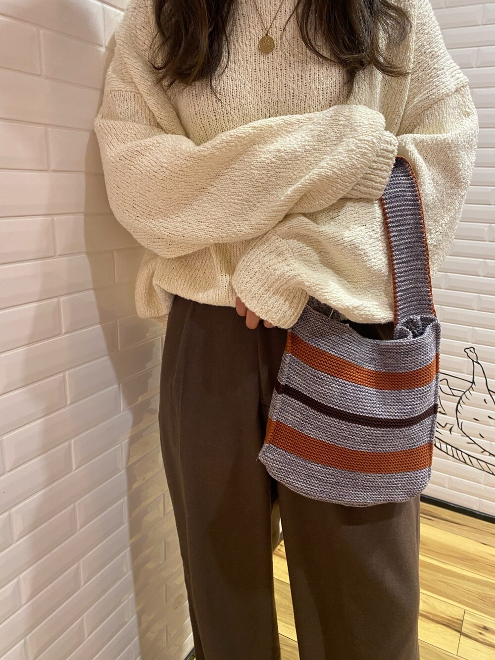 ホワイト系のニット/セーター、ブラウン系のその他パンツ、グレー系のハンドバッグを着用したレディースの冬コーディネートの6枚目の写真