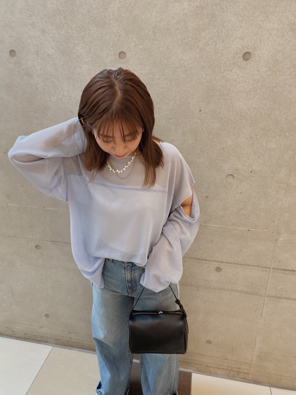 ブルー系のニット/セーター、ブルー系のデニムパンツ、ブラック系のハンドバッグを着用したレディースの春コーディネートの4枚目の写真