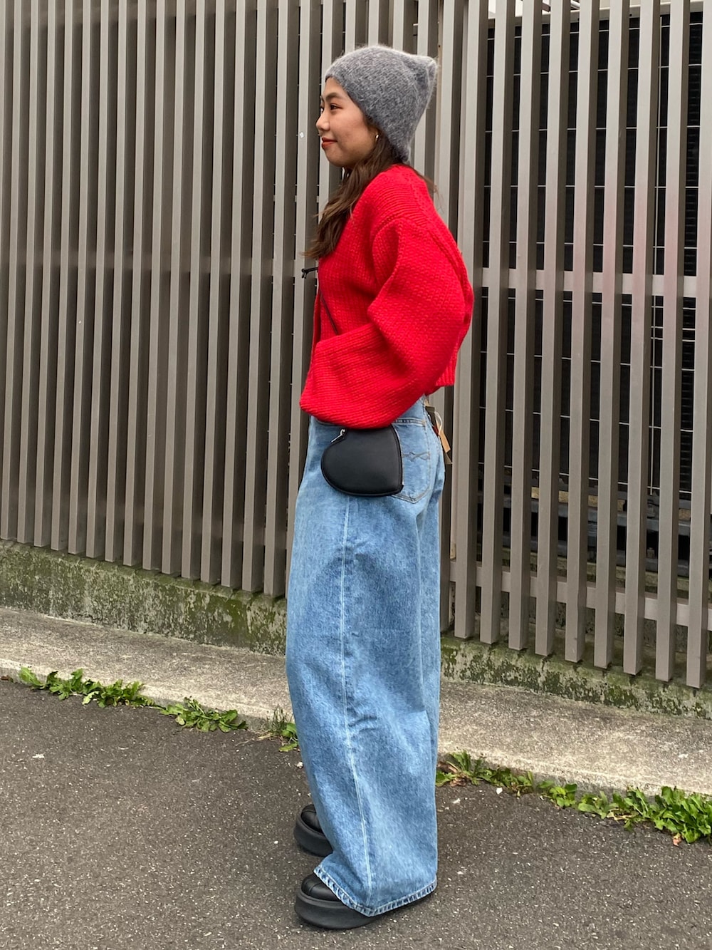 レッド系のカーディガン/ボレロ、ブルー系のデニムパンツ、ブラック系のショルダーバッグを着用したレディースの冬コーディネートの2枚目の写真