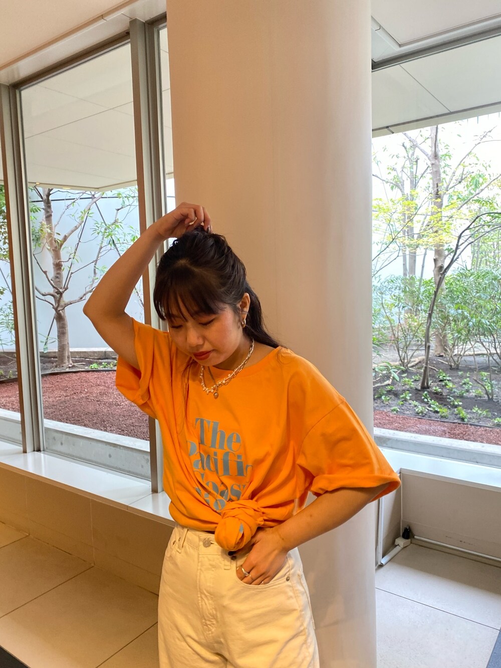 オレンジ系のTシャツ/カットソー、ホワイト系のデニムパンツを着用したレディースの春コーディネートの4枚目の写真