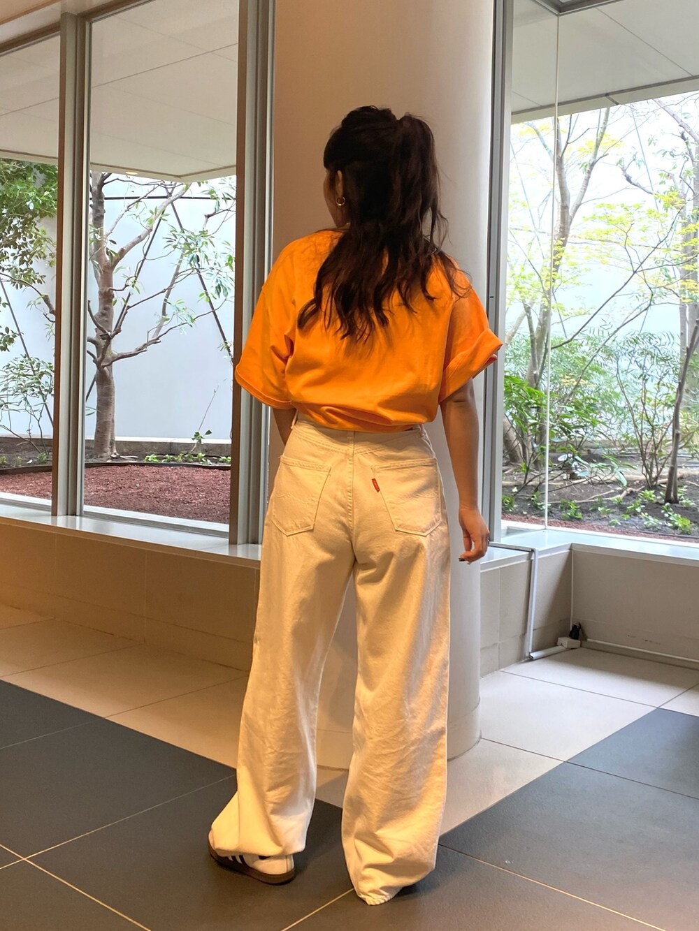 オレンジ系のTシャツ/カットソー、ホワイト系のデニムパンツを着用したレディースの春コーディネートの3枚目の写真