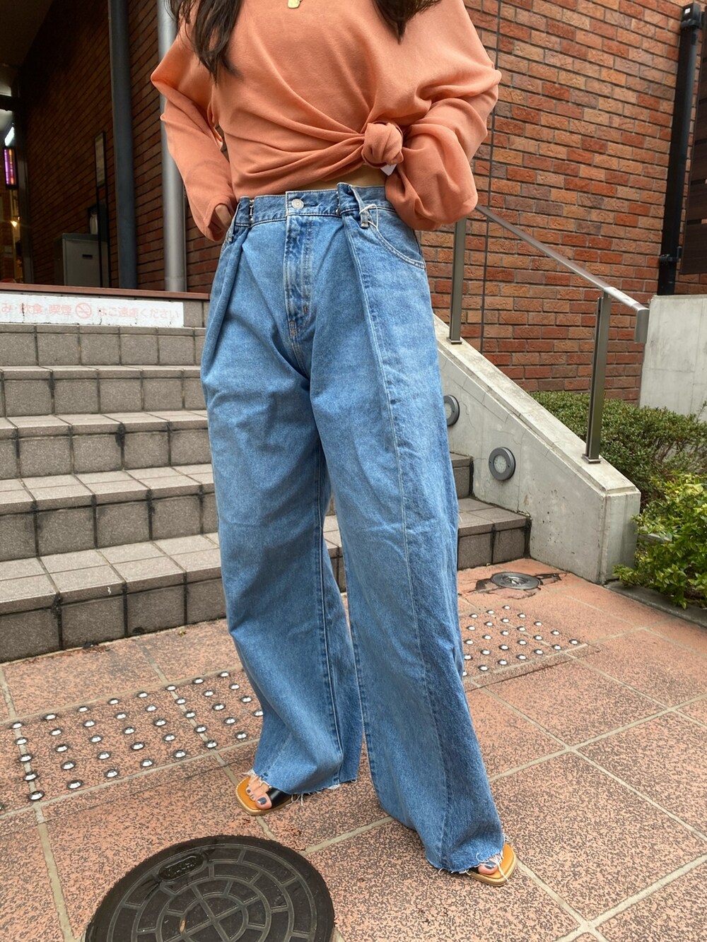 オレンジ系のニット/セーター、ブルー系のデニムパンツ、ブラック系のサンダルを着用したレディースの春コーディネートの5枚目の写真