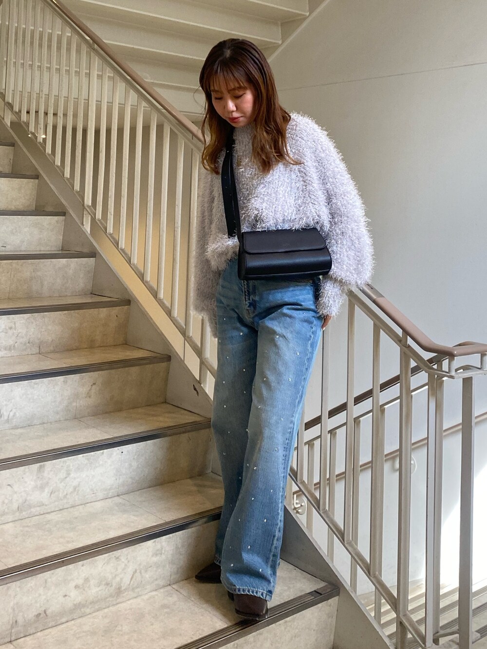 ブラック系のニット/セーター、ブルー系のデニムパンツ、ブラウン系のブーツを着用したレディースの秋コーディネートの2枚目の写真