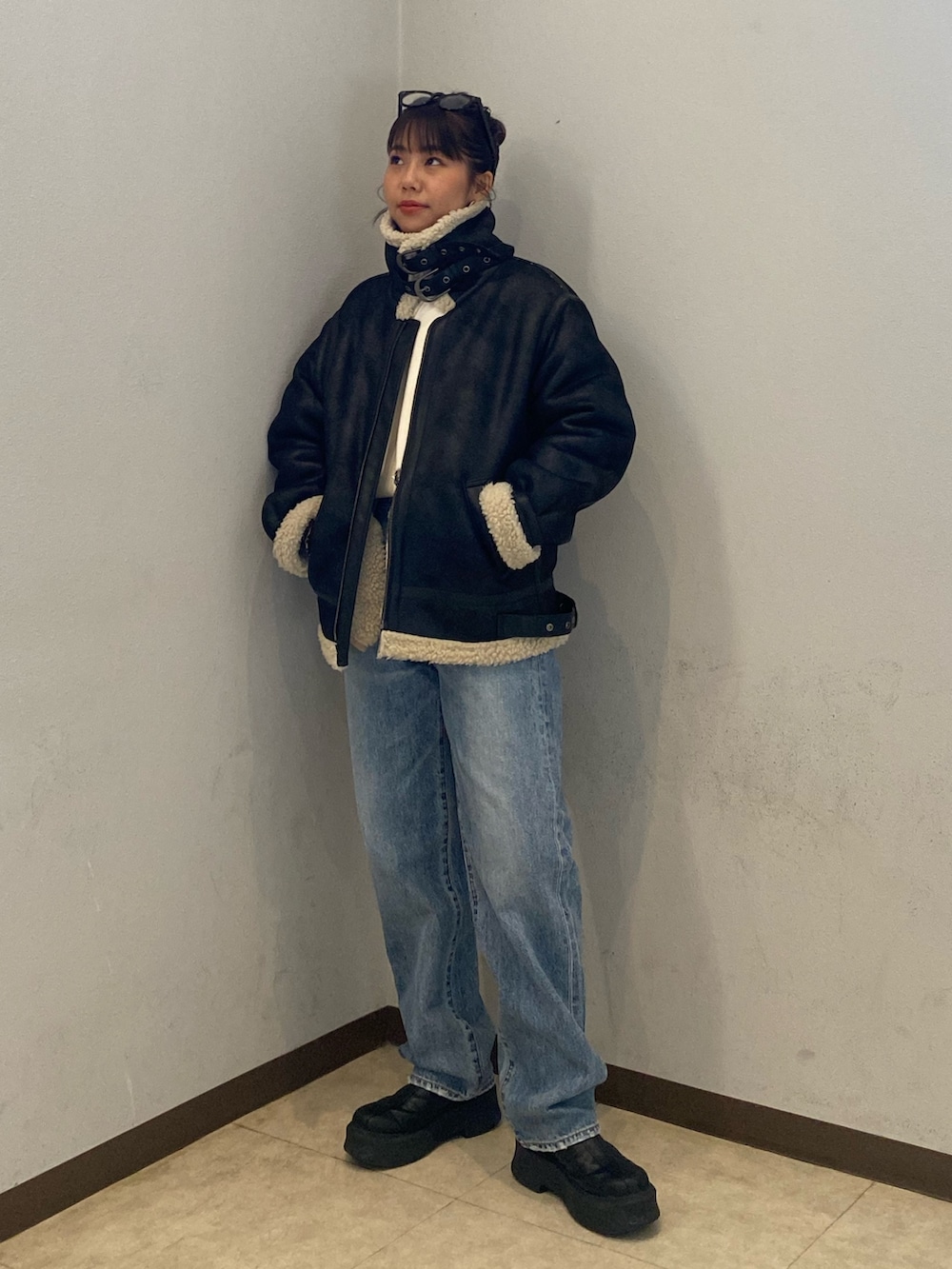 ブラック系のムートンコート、ブルー系のデニムパンツを着用したレディースの冬コーディネートの2枚目の写真