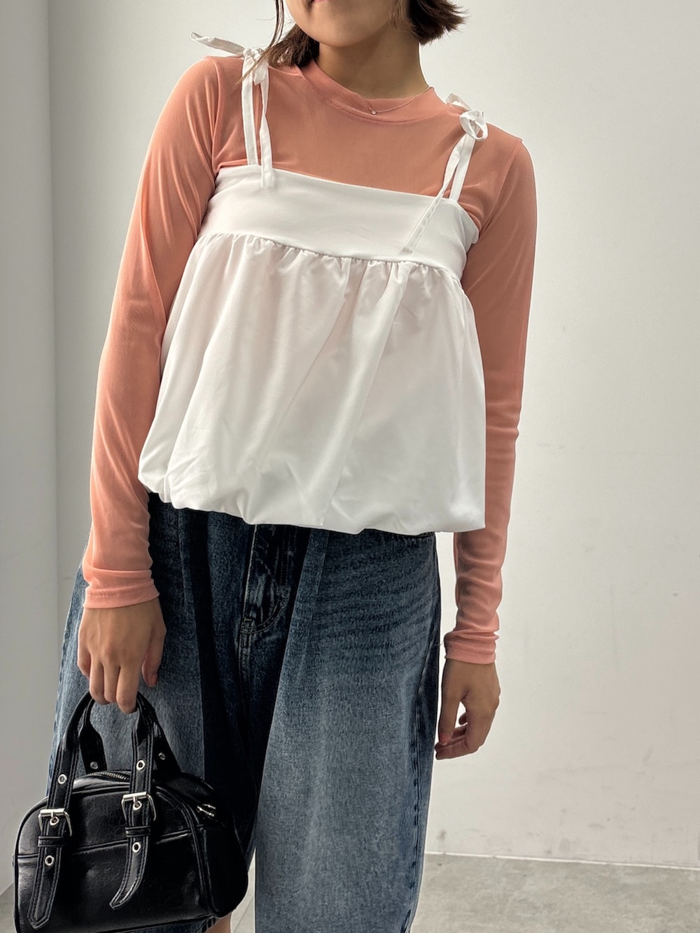 ブラック系のスニーカー、ブラック系のショルダーバッグ、ブルー系のデニムパンツを着用したレディースの夏コーディネートの2枚目の写真