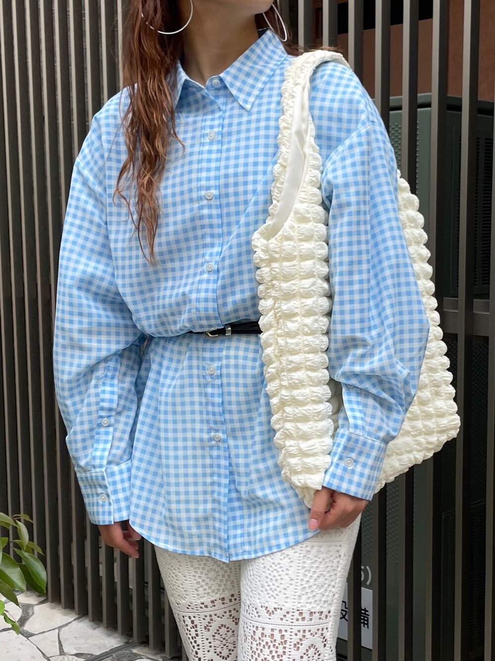 ブルー系のシャツ/ブラウス、ホワイト系のスラックス、ホワイト系のトートバッグを着用したレディースの春コーディネートの2枚目の写真