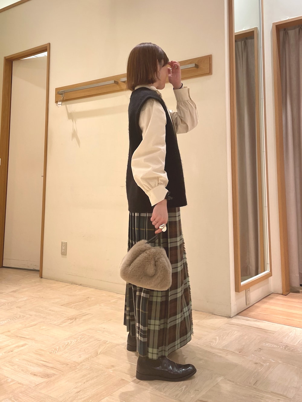 ホワイト系のシャツ/ブラウス、ブラック系のベスト、ベージュ系のショルダーバッグを着用したレディースの冬コーディネートの3枚目の写真