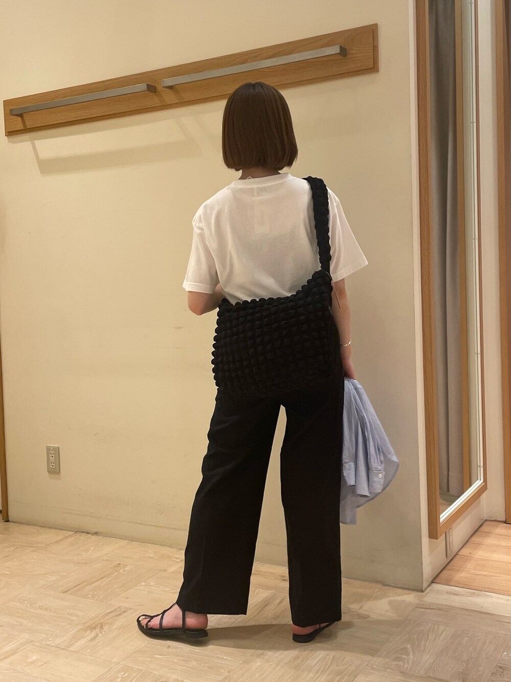 ブラック系のスラックス、ブルー系のシャツ/ブラウス、ブラック系のショルダーバッグを着用したレディースの夏コーディネートの2枚目の写真