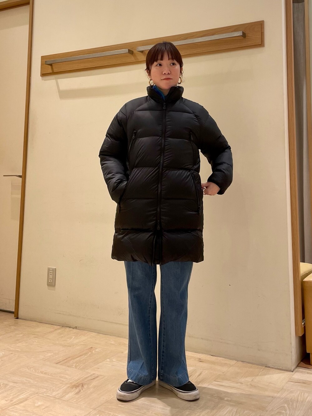 ブルー系のデニムパンツ、ブラック系のダウンジャケット/コート、ゴールド系のピアス（両耳用）を着用したレディースの冬コーディネートの2枚目の写真