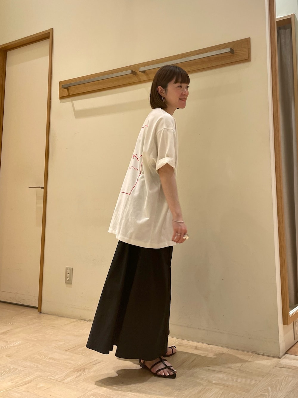 ホワイト系のTシャツ/カットソー、ブラック系のスカート、ブラック系のサンダルを着用したレディースの春コーディネートの4枚目の写真