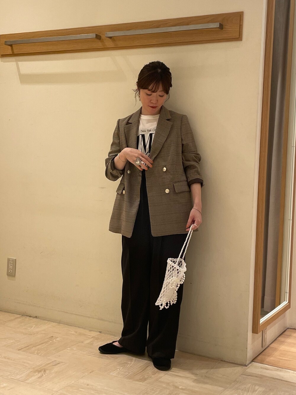 ベージュ系のテーラードジャケット、ホワイト系のTシャツ/カットソー、ブラック系のスラックスを着用したレディースの夏コーディネートの3枚目の写真