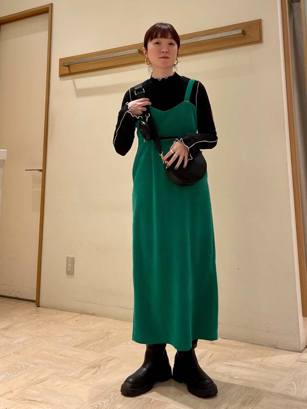 グリーン系のワンピース、ブラック系のブーツ、ブルー系のTシャツ/カットソーを着用したレディースの冬コーディネートの2枚目の写真