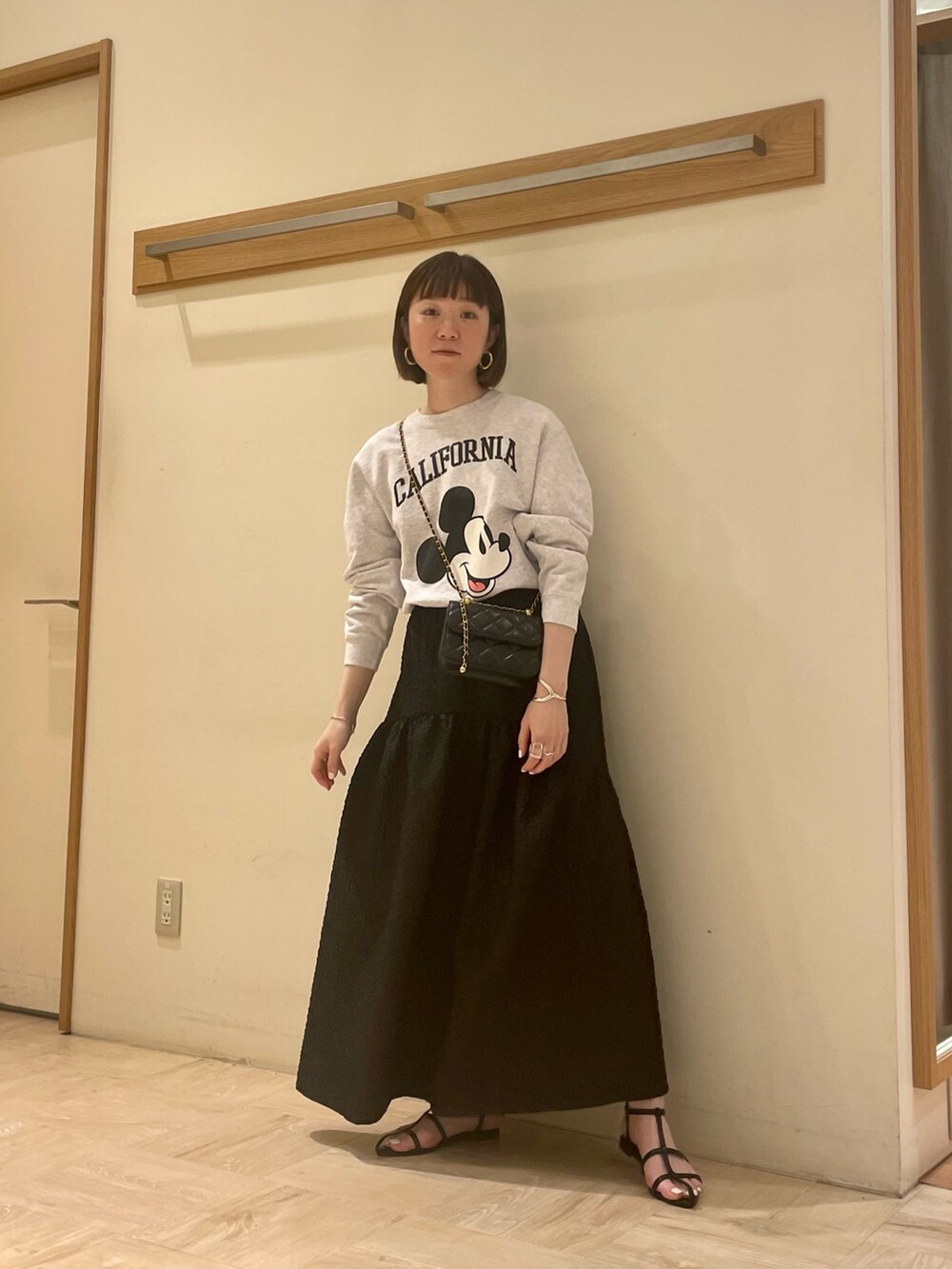 グレー系のスウェット、ブラック系のスカート、ブラック系のショルダーバッグを着用したレディースの春コーディネートの3枚目の写真