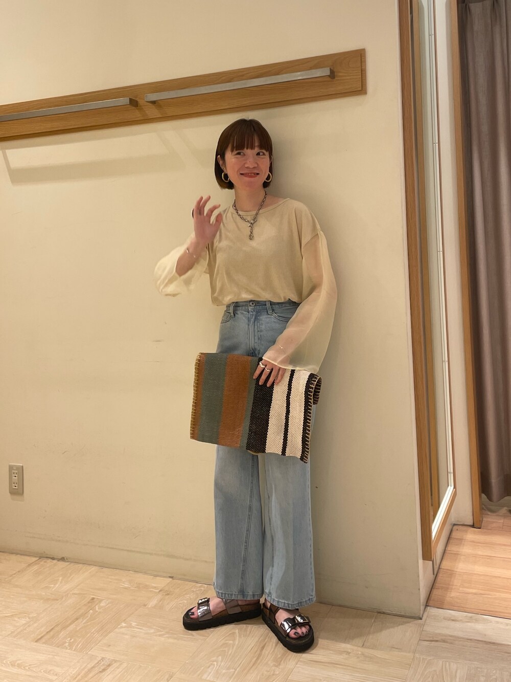 グレー系のサンダル、グリーン系のトートバッグ、ブルー系のデニムパンツを着用したレディースの春コーディネートの3枚目の写真