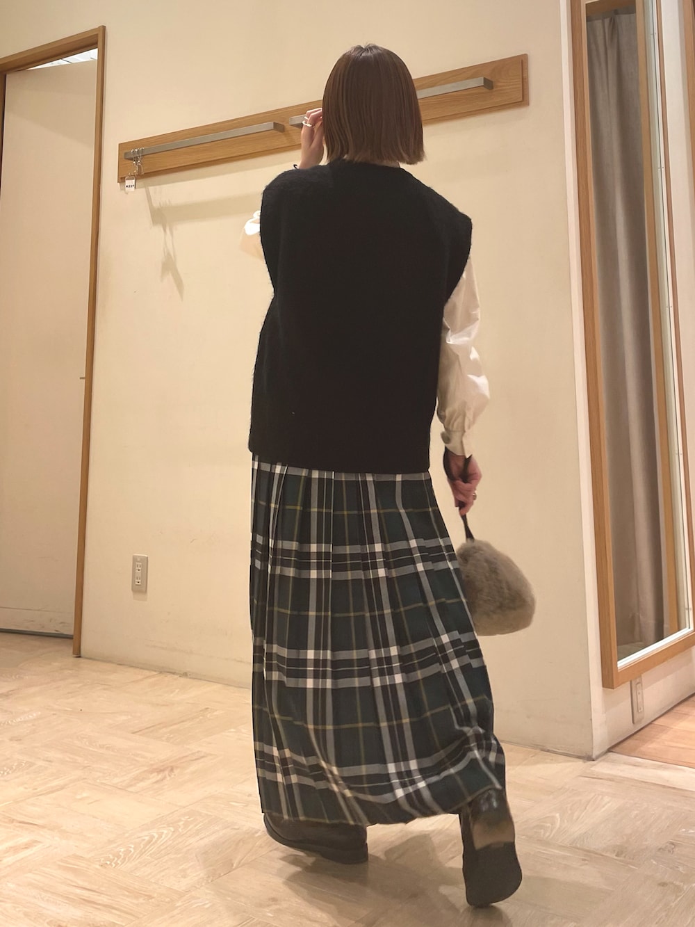 ホワイト系のシャツ/ブラウス、ブラック系のベスト、ベージュ系のショルダーバッグを着用したレディースの冬コーディネートの4枚目の写真