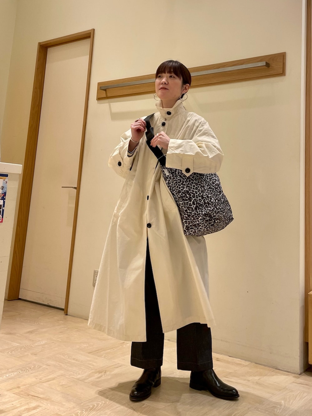 ホワイト系のステンカラーコート、ホワイト系のショルダーバッグ、ブルー系のTシャツ/カットソーを着用したレディースの冬コーディネートの2枚目の写真