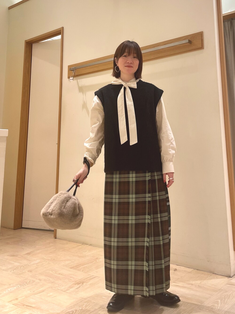 ホワイト系のシャツ/ブラウス、ブラック系のベスト、ベージュ系のショルダーバッグを着用したレディースの冬コーディネートの2枚目の写真