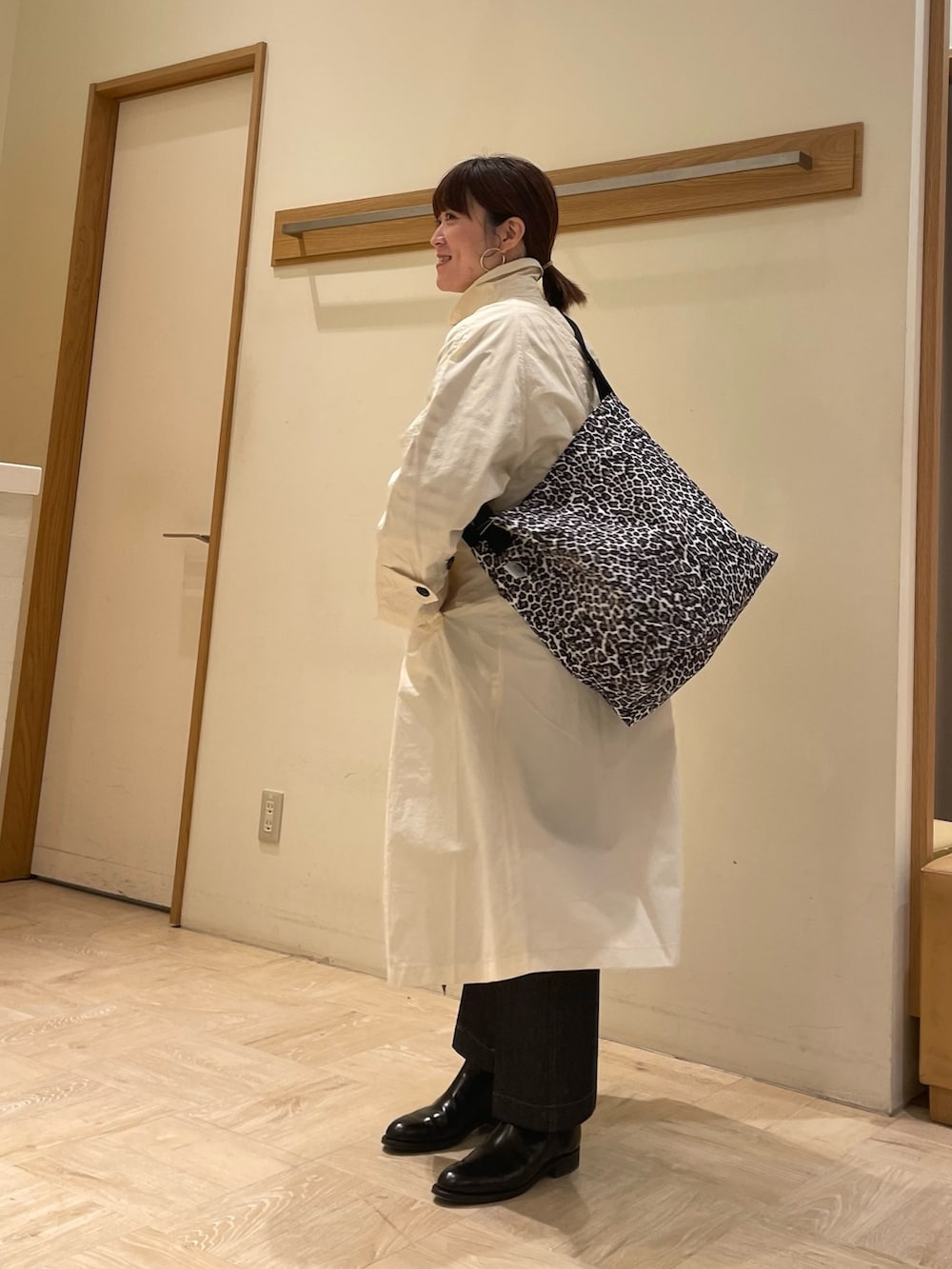 ホワイト系のステンカラーコート、ホワイト系のショルダーバッグ、ブルー系のTシャツ/カットソーを着用したレディースの冬コーディネートの3枚目の写真