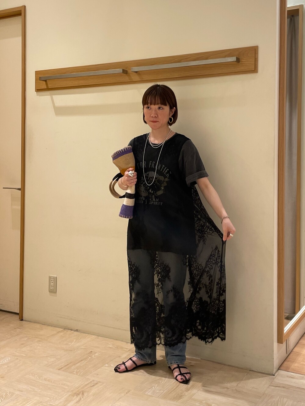 ブルー系のトートバッグ、グレー系のTシャツ/カットソー、ブラック系のベストを着用したレディースの春コーディネートの2枚目の写真