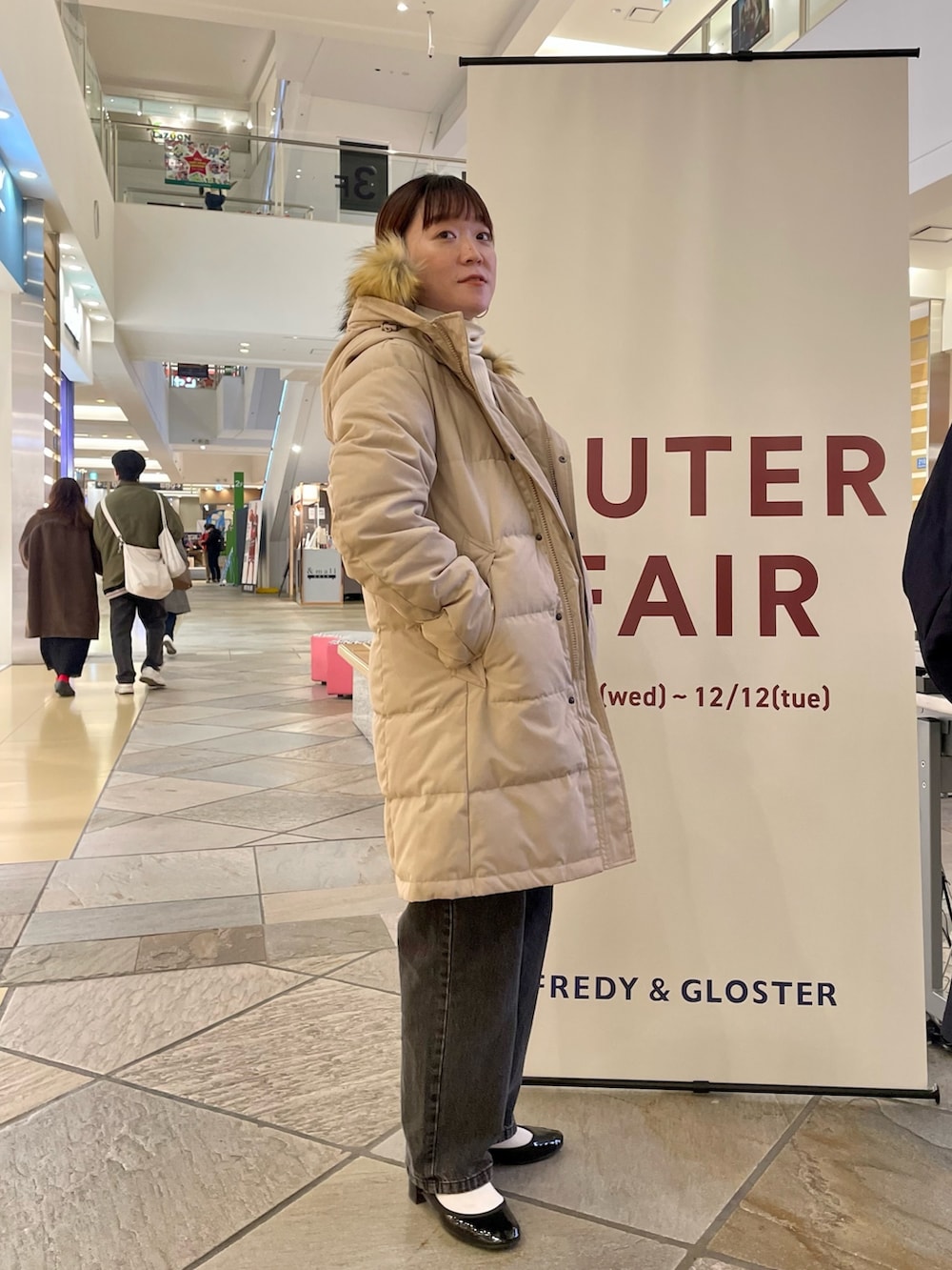 ベージュ系のダウンジャケット/コート、ブラック系のデニムパンツを着用したレディースの冬コーディネートの2枚目の写真