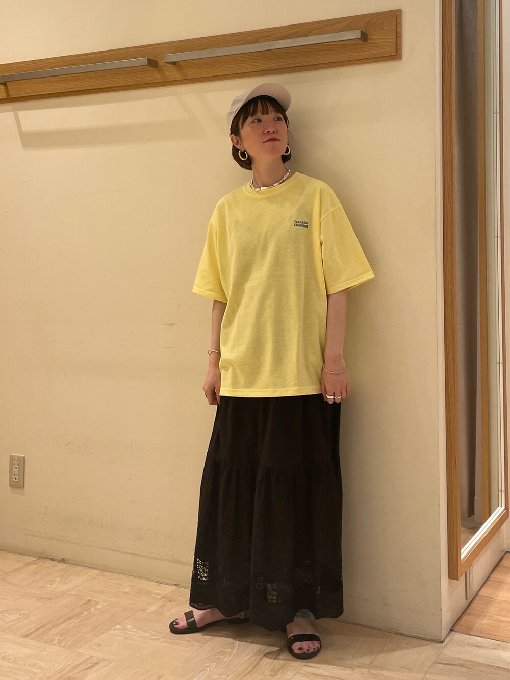ブラック系のスカート、イエロー系のTシャツ/カットソー、ホワイト系のキャップを着用したレディースの春コーディネートの3枚目の写真