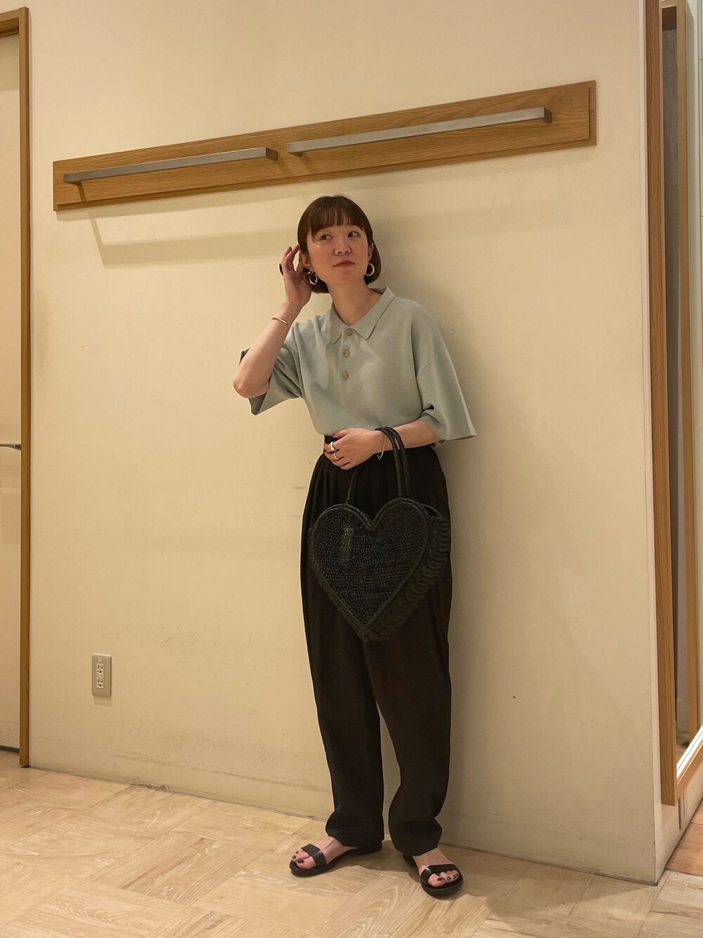 グリーン系のポロシャツ、ブラック系のバッグ、ブラック系のその他パンツを着用したレディースの春コーディネートの2枚目の写真