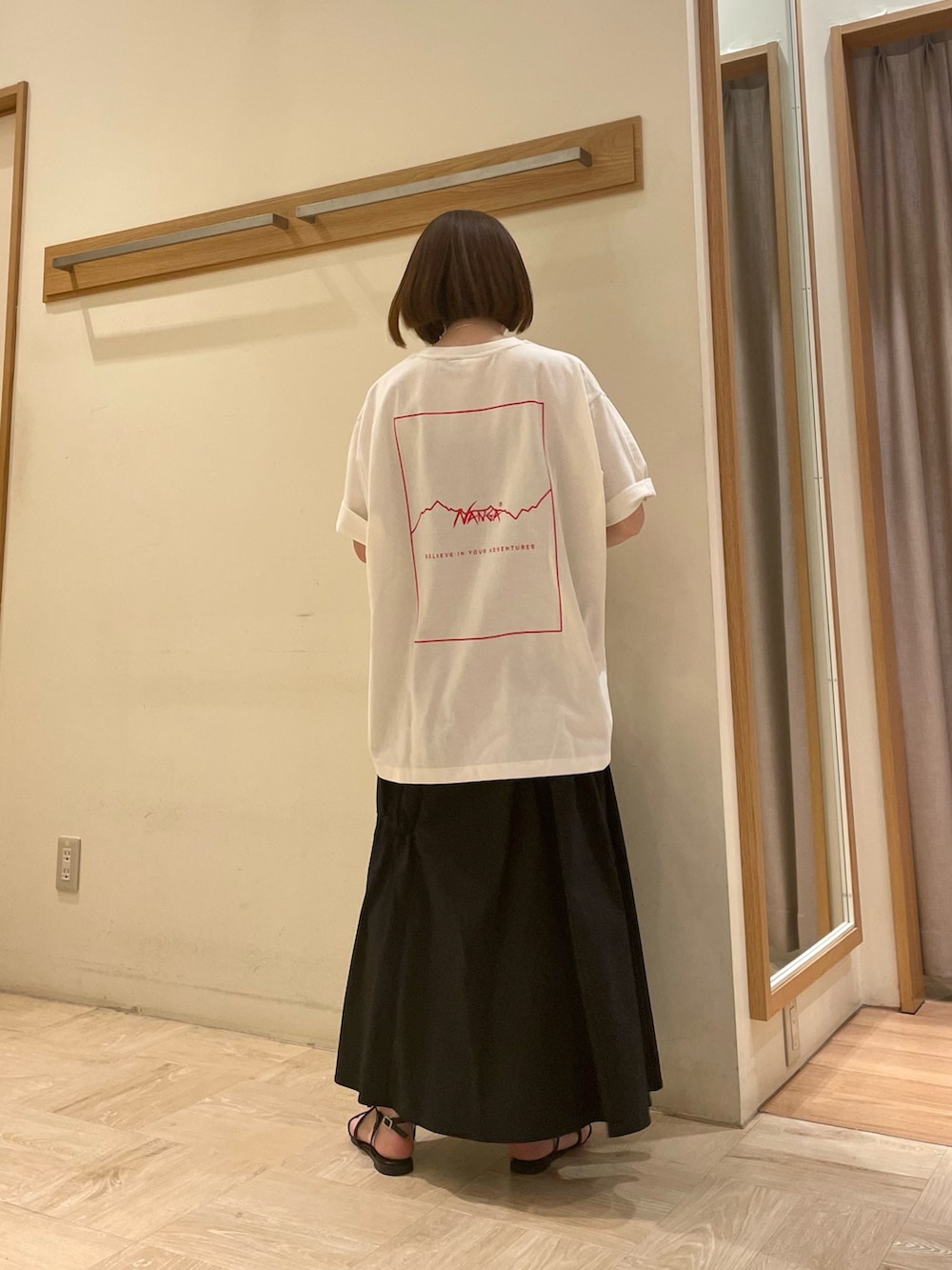 ホワイト系のTシャツ/カットソー、ブラック系のスカート、ブラック系のサンダルを着用したレディースの春コーディネートの3枚目の写真