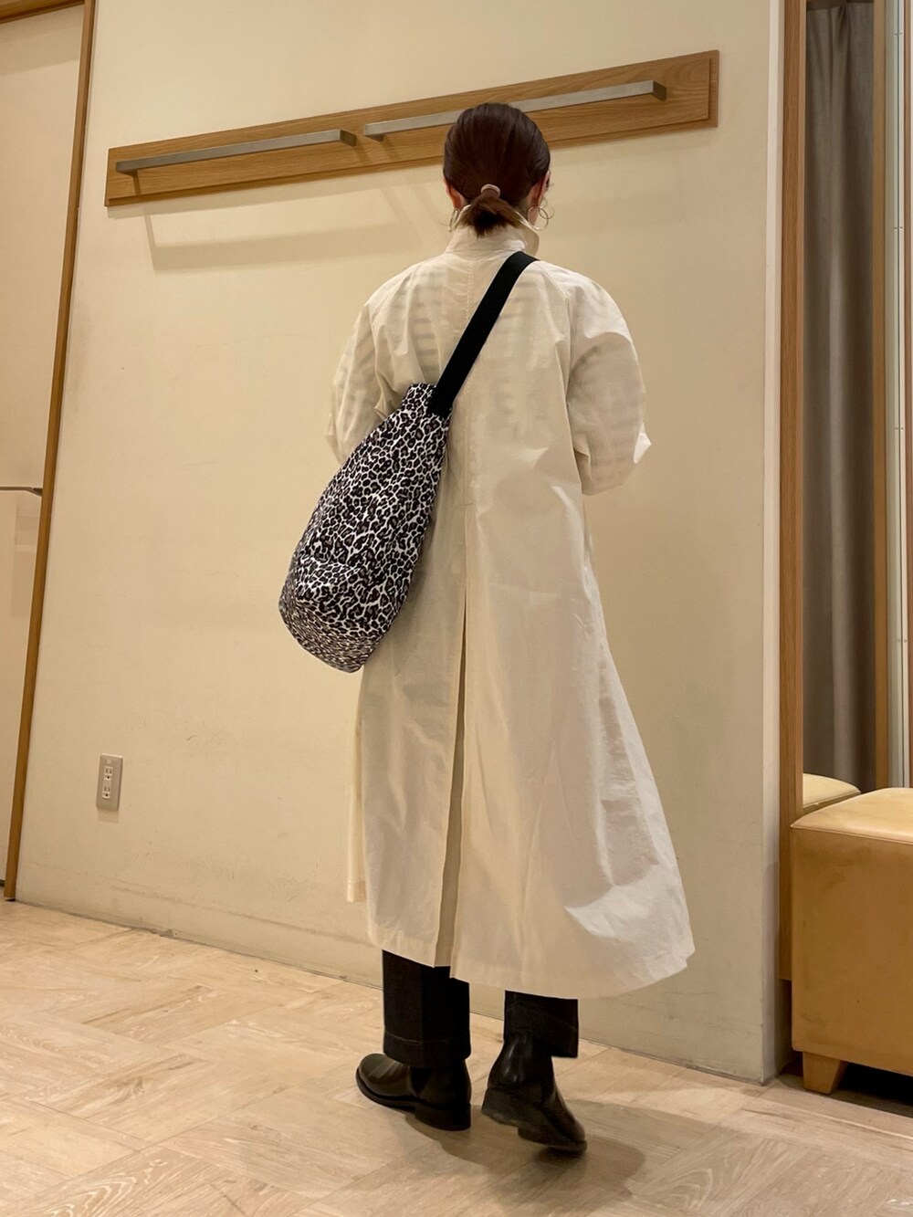 ホワイト系のステンカラーコート、ホワイト系のショルダーバッグ、ブルー系のTシャツ/カットソーを着用したレディースの冬コーディネートの4枚目の写真