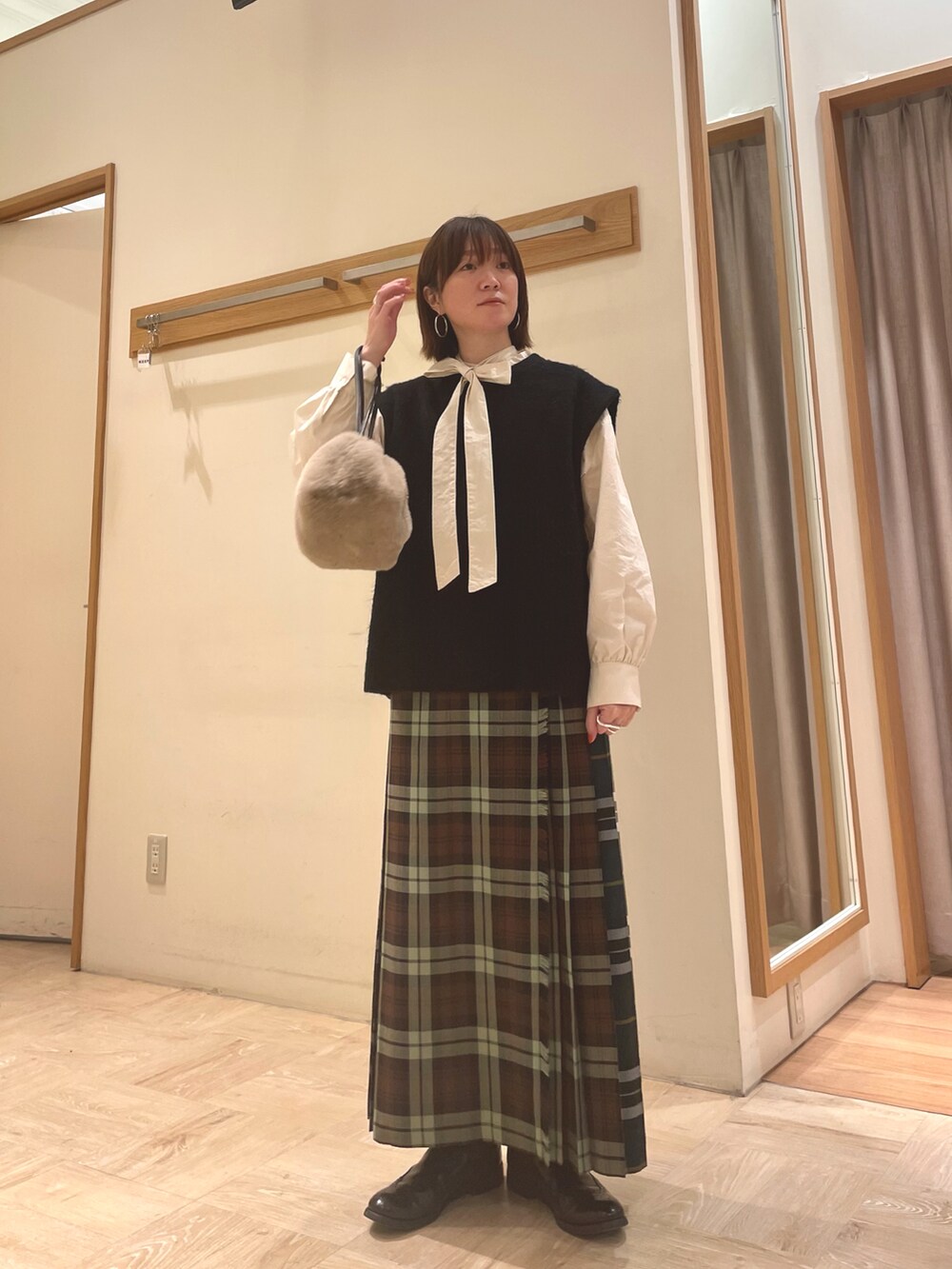 ホワイト系のシャツ/ブラウス、ブラック系のベスト、ベージュ系のショルダーバッグを着用したレディースの冬コーディネートの5枚目の写真