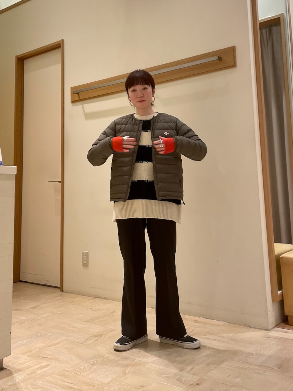 ホワイト系のニット/セーター、グリーン系のダウンジャケット/コート、オレンジ系の手袋を着用したレディースの冬コーディネートの2枚目の写真