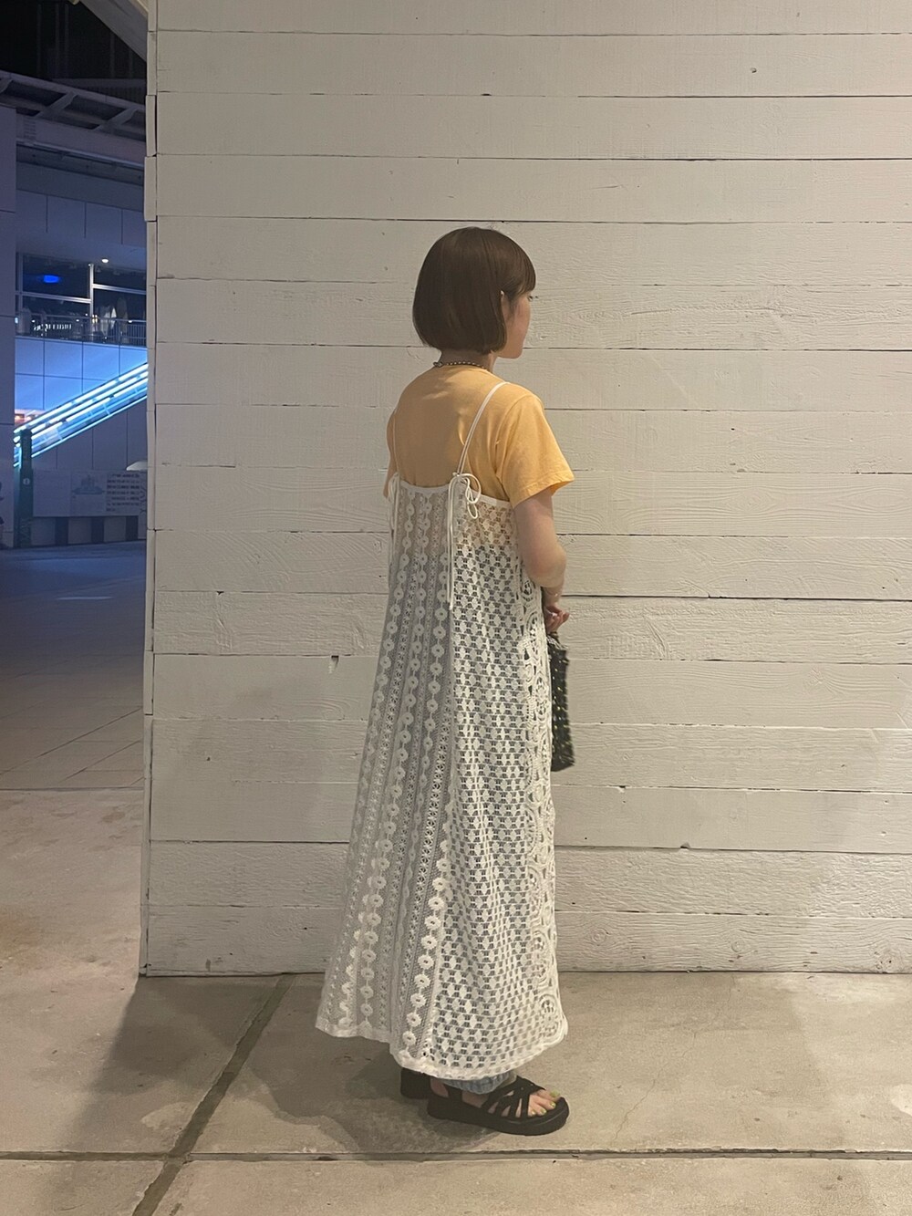 オレンジ系のTシャツ/カットソー、ブラック系のトートバッグ、ブルー系のデニムパンツを着用したレディースの夏コーディネートの2枚目の写真