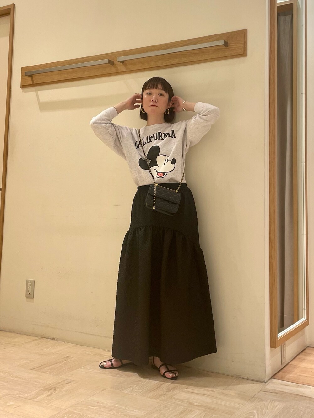 グレー系のスウェット、ブラック系のスカート、ブラック系のショルダーバッグを着用したレディースの春コーディネートの2枚目の写真