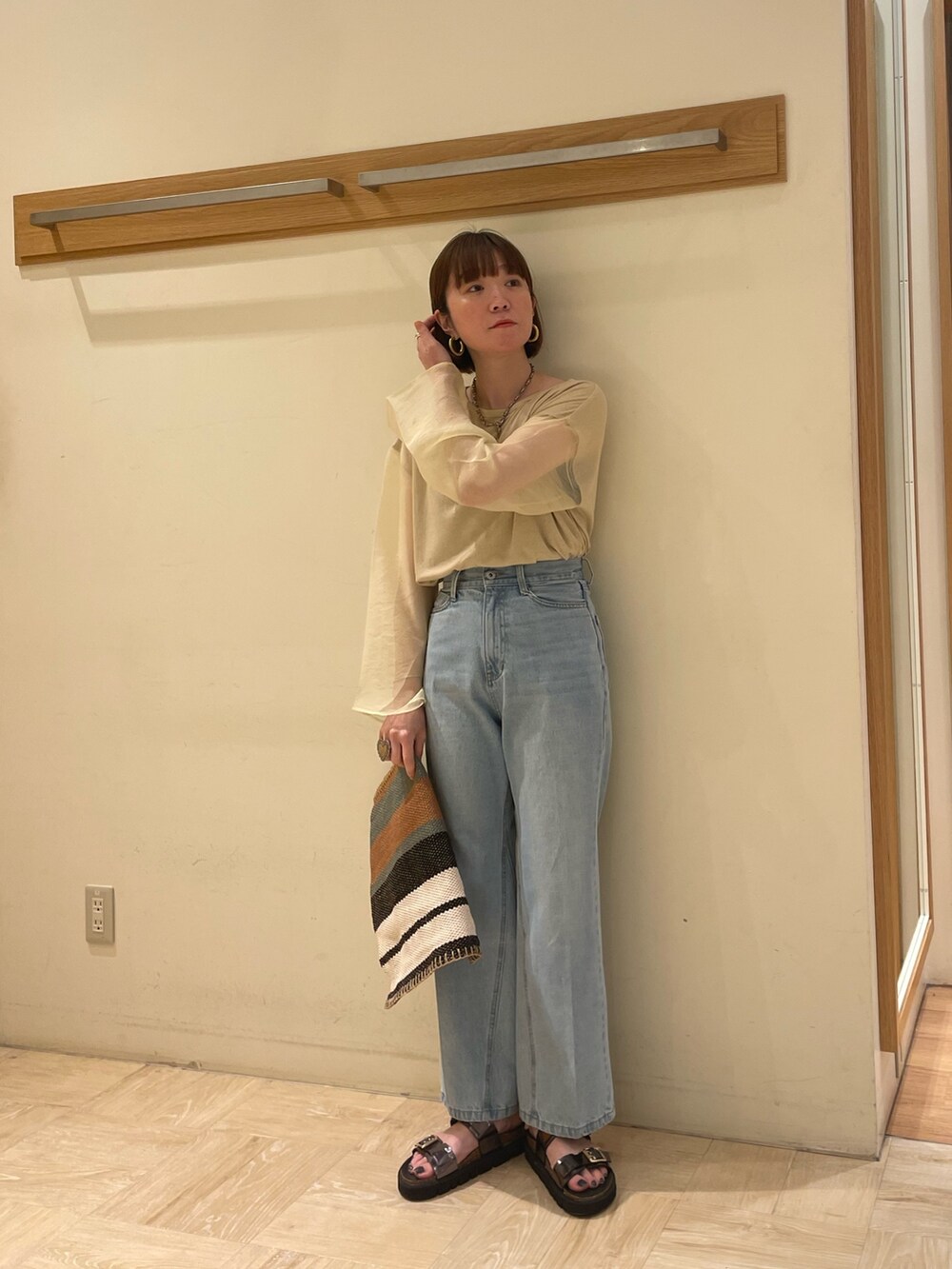 グレー系のサンダル、グリーン系のトートバッグ、ブルー系のデニムパンツを着用したレディースの春コーディネートの2枚目の写真