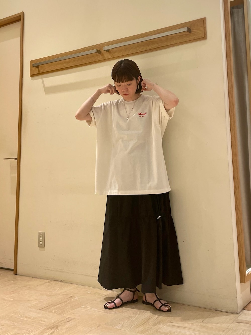 ホワイト系のTシャツ/カットソー、ブラック系のスカート、ブラック系のサンダルを着用したレディースの春コーディネートの2枚目の写真