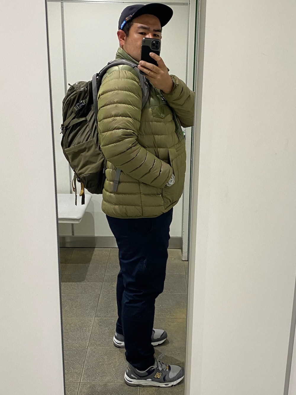 グリーン系のジャケット/アウター、ブルー系のパンツ、グレー系のスニーカーを着用したメンズの冬コーディネートの2枚目の写真