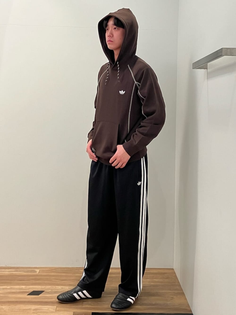 ブラウン系のパーカー、ブラック系のスウェットパンツ、ブラック系のシューズを着用したメンズの冬コーディネートの2枚目の写真