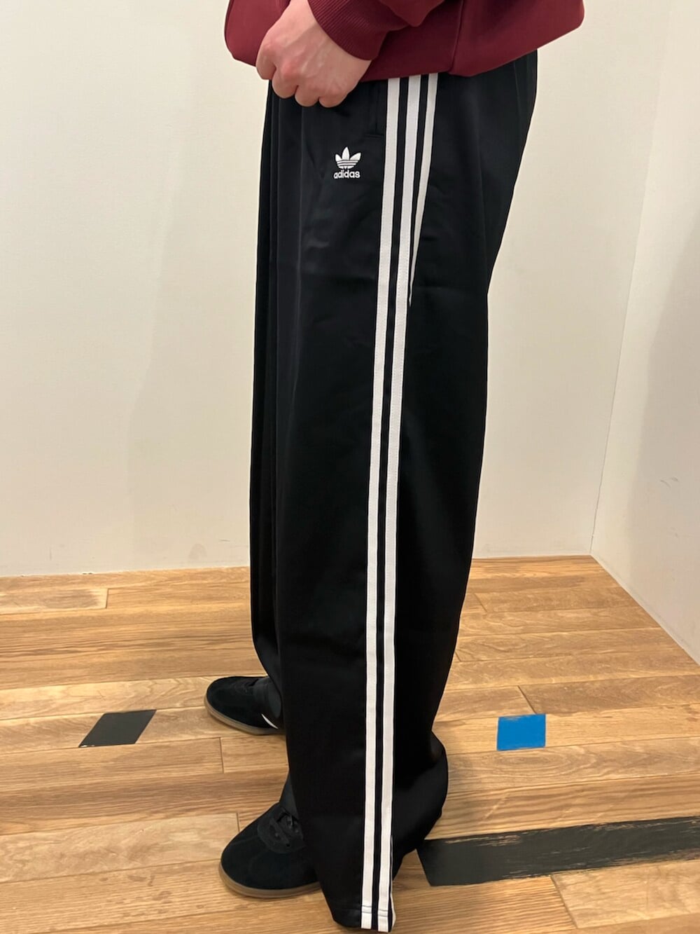 レッド系のパーカー、ブラック系のスウェットパンツ、ブラック系のスニーカーを着用したメンズの冬コーディネートの3枚目の写真