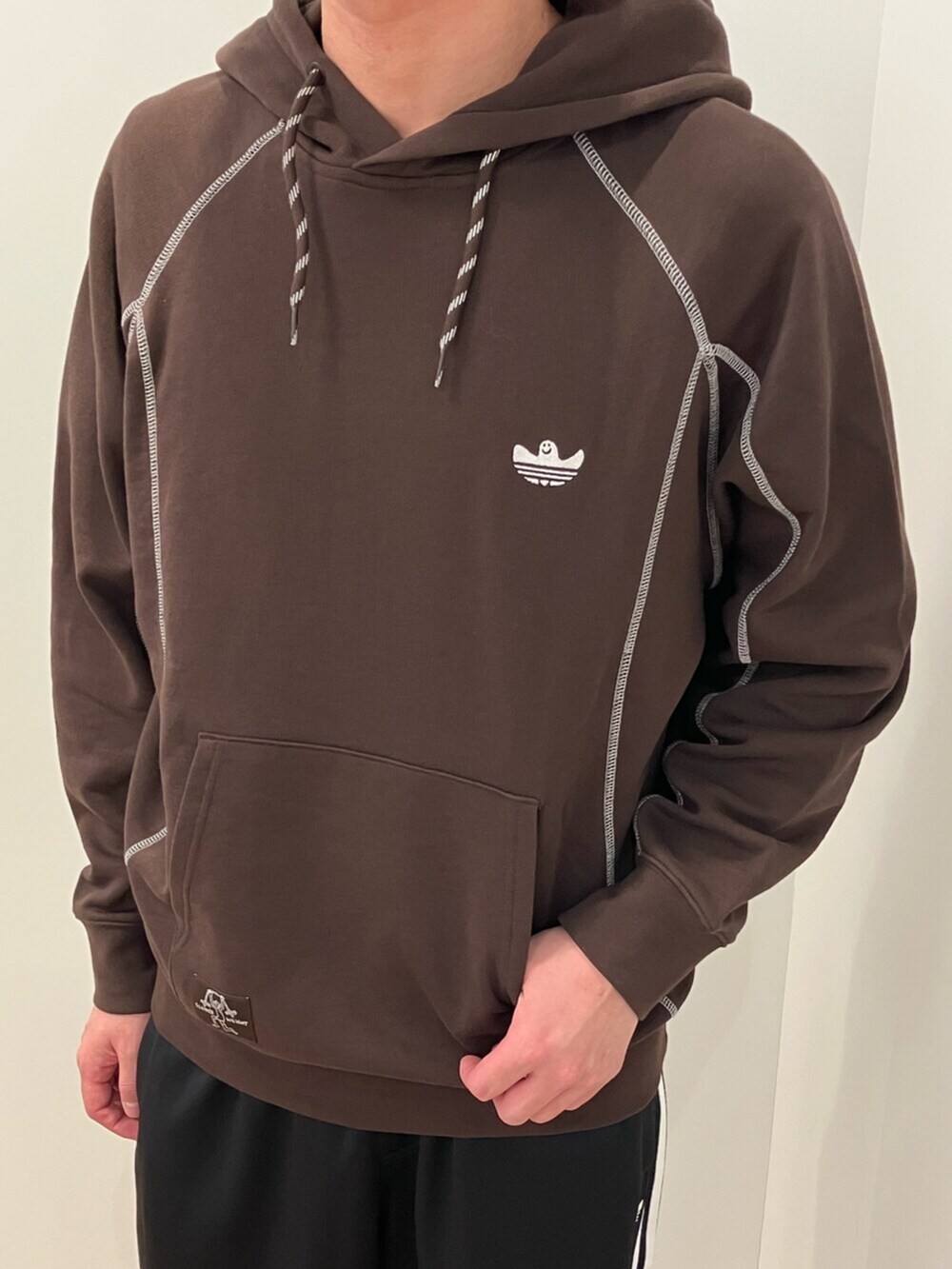 ブラウン系のパーカー、ブラック系のスウェットパンツ、ブラック系のシューズを着用したメンズの冬コーディネートの3枚目の写真