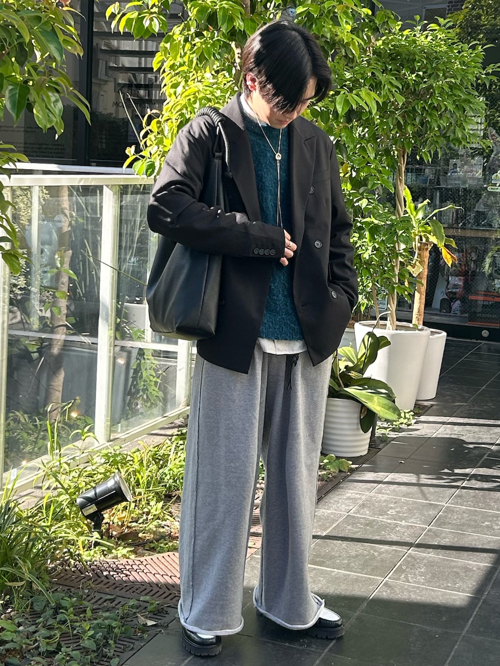 ブラック系のテーラードジャケット、ブラック系のローファー、ブルー系のニット/セーターを着用したメンズの秋コーディネートの2枚目の写真