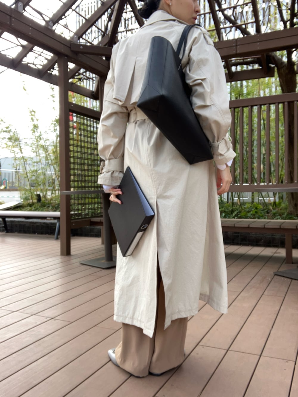 ベージュ系のパンツ、ベージュ系のトレンチコート、グレー系のトートバッグを着用したレディースの春コーディネートの2枚目の写真