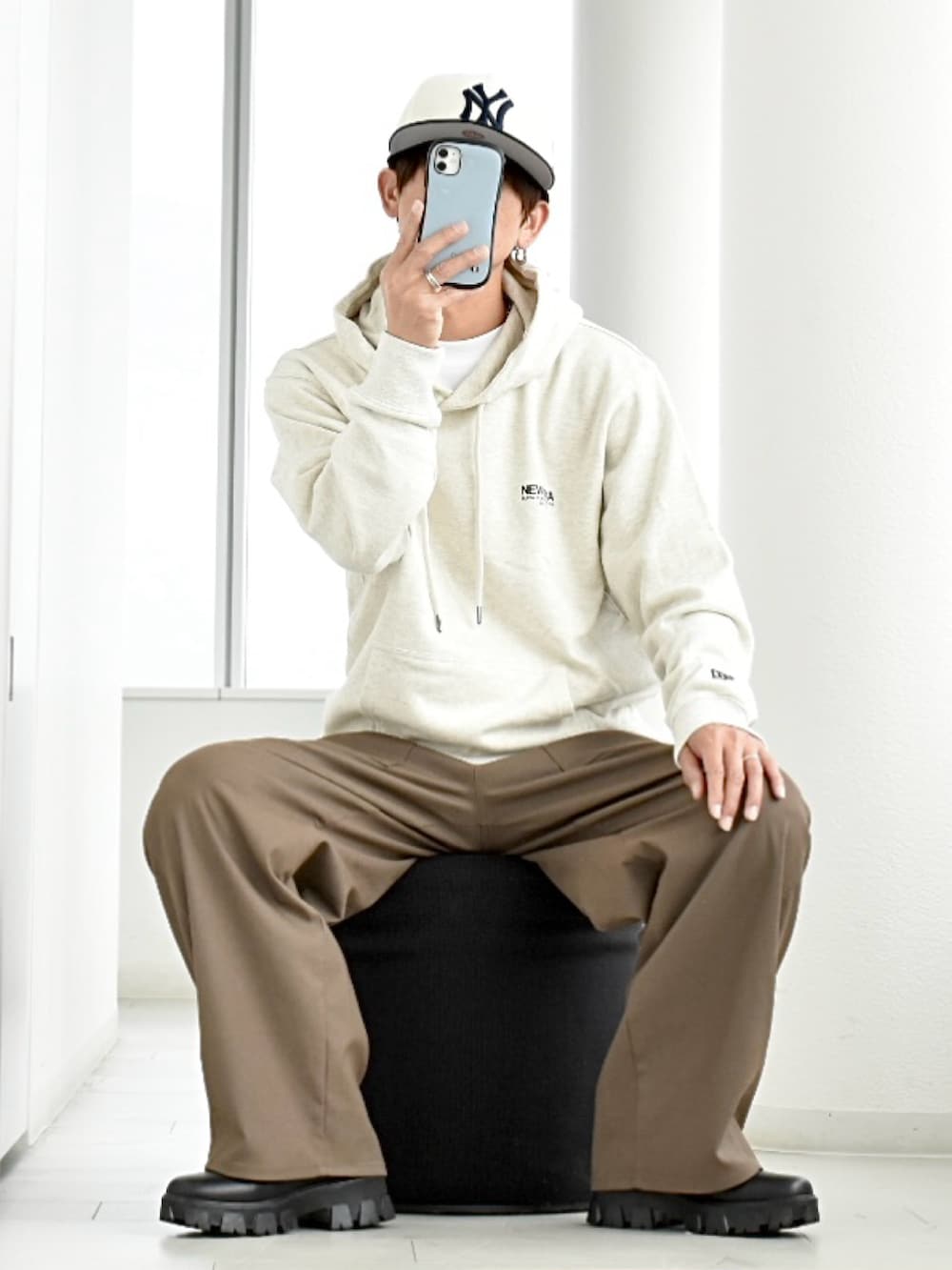 ブラック系のブーツ、ホワイト系のパーカー、ベージュ系のパンツを着用したメンズの秋コーディネートの2枚目の写真