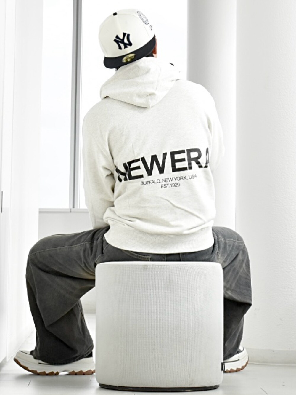 ブラック系のデニムパンツ、ホワイト系のパーカー、ブラック系のスニーカーを着用したメンズの冬コーディネートの4枚目の写真