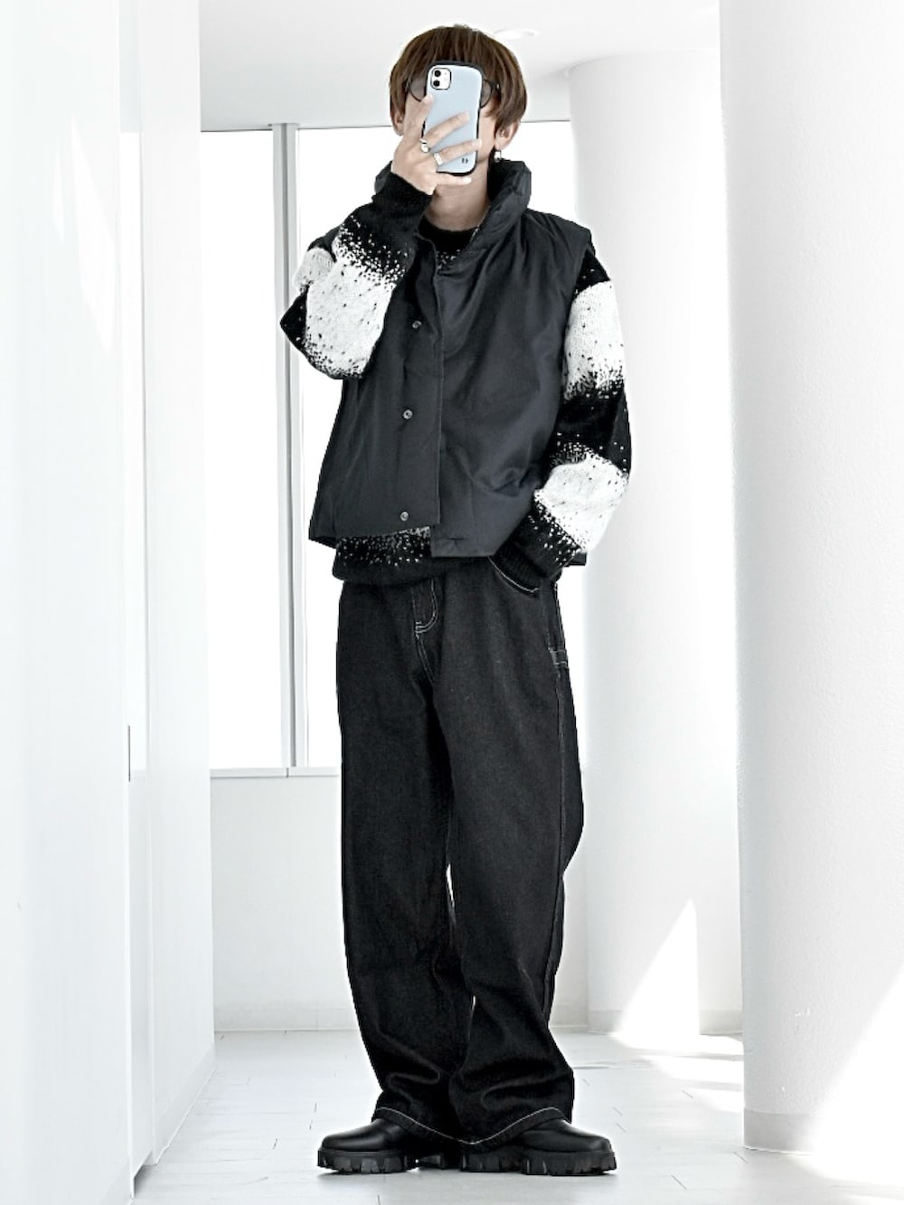 ブラック系のニット/セーター、ブラック系のダウンベスト、ブラック系のデニムパンツを着用したメンズの秋コーディネートの2枚目の写真