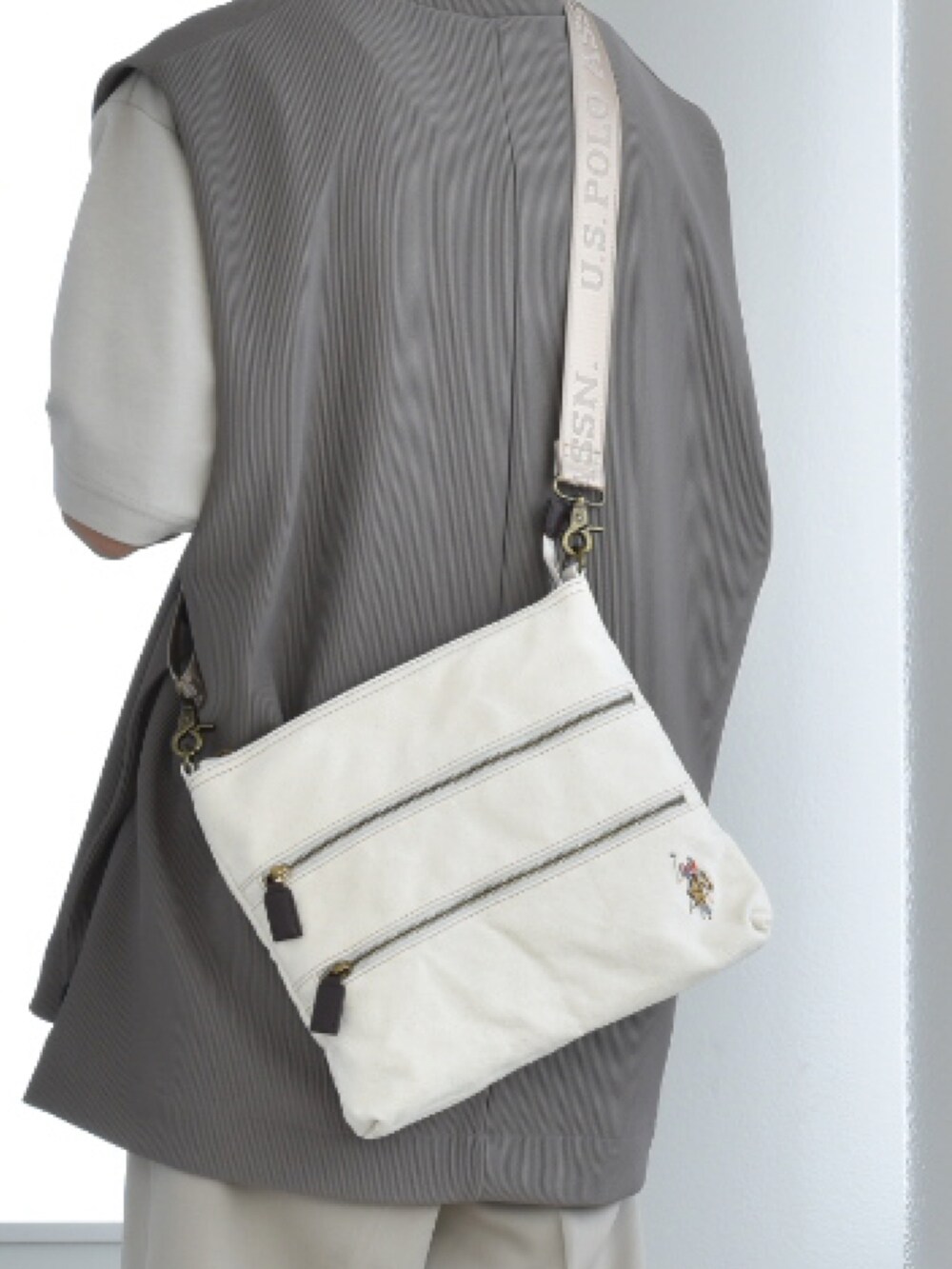 ホワイト系のショルダーバッグ、グレー系のベスト、ベージュ系のTシャツ/カットソーを着用したメンズの春コーディネートの2枚目の写真