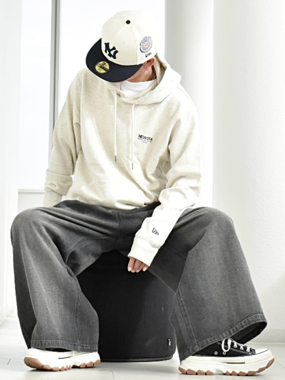 ブラック系のデニムパンツ、ホワイト系のパーカー、ブラック系のスニーカーを着用したメンズの冬コーディネートの3枚目の写真