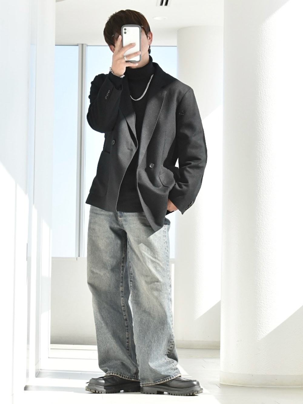 ブラック系のニット/セーター、ブラック系のジャケット/アウター、ブルー系のデニムパンツを着用したメンズの春コーディネートの2枚目の写真